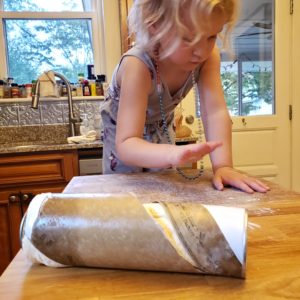 Roll of Pillsbury Pizza Dough with blonde girl in background