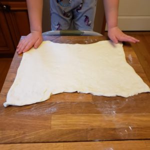 Pillsbury Pizza Dough stretched out over a floured butcher block