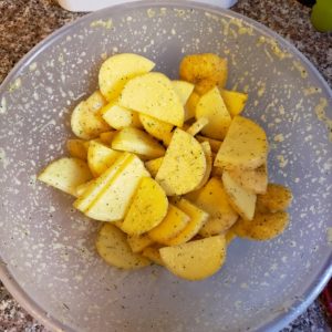 Seasoned potatoes in a mixing bowl.