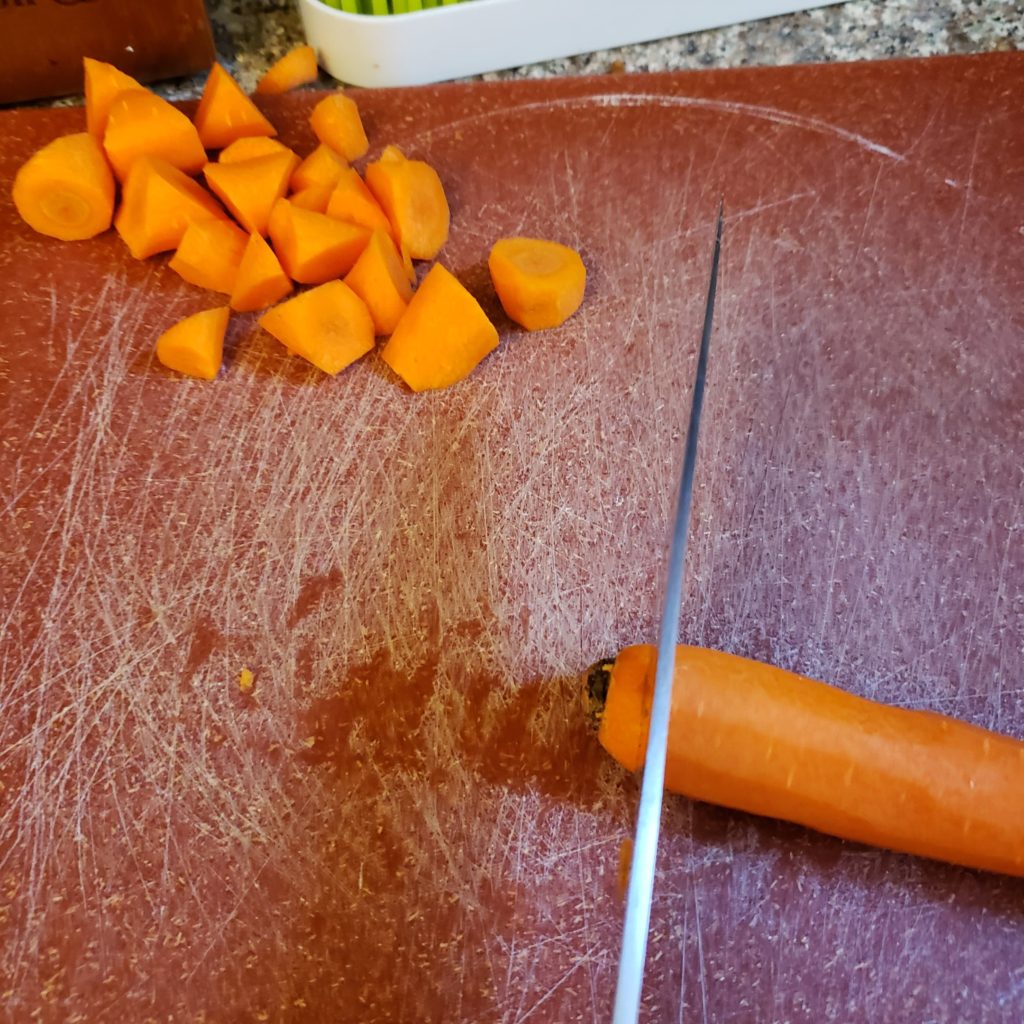 carrot and pieces on a red cutting board