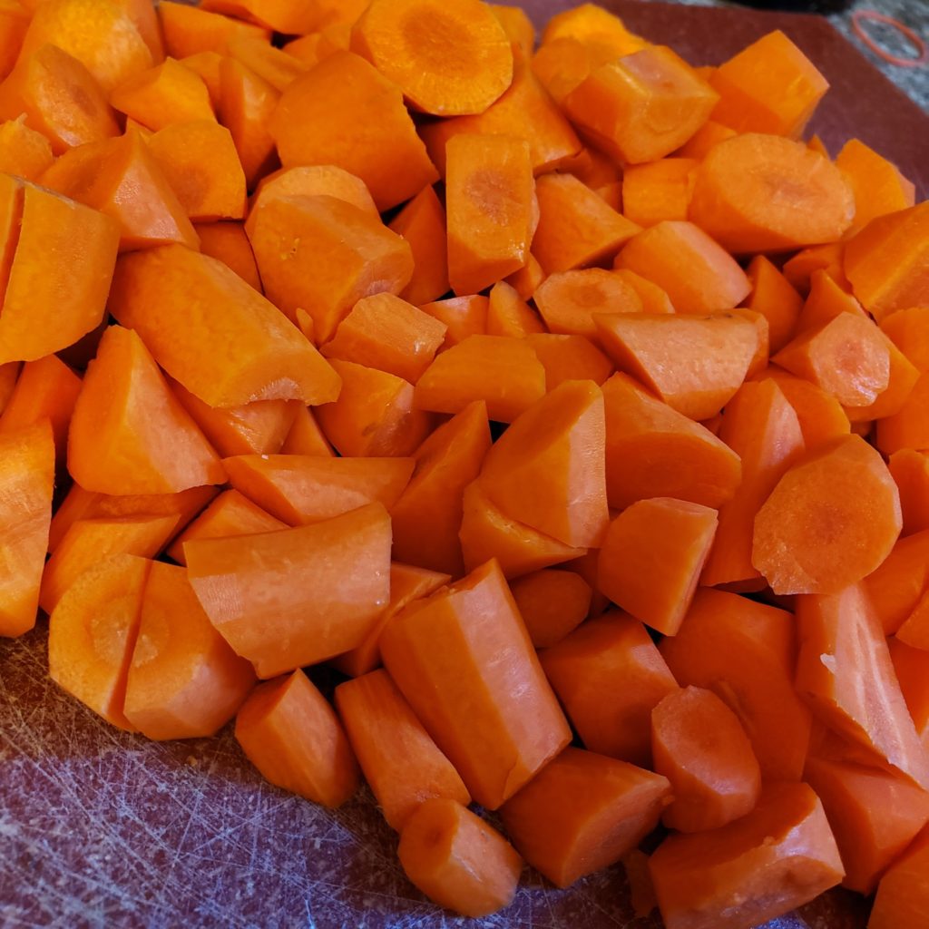 Oblique cut carrots on a red cutting board