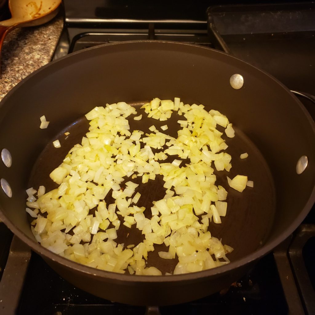 Sautéed onions in a pan for smokey white chicken chili