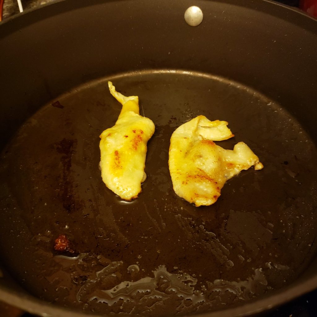 Chicken skin cooking in a saute pan to create schmaltz