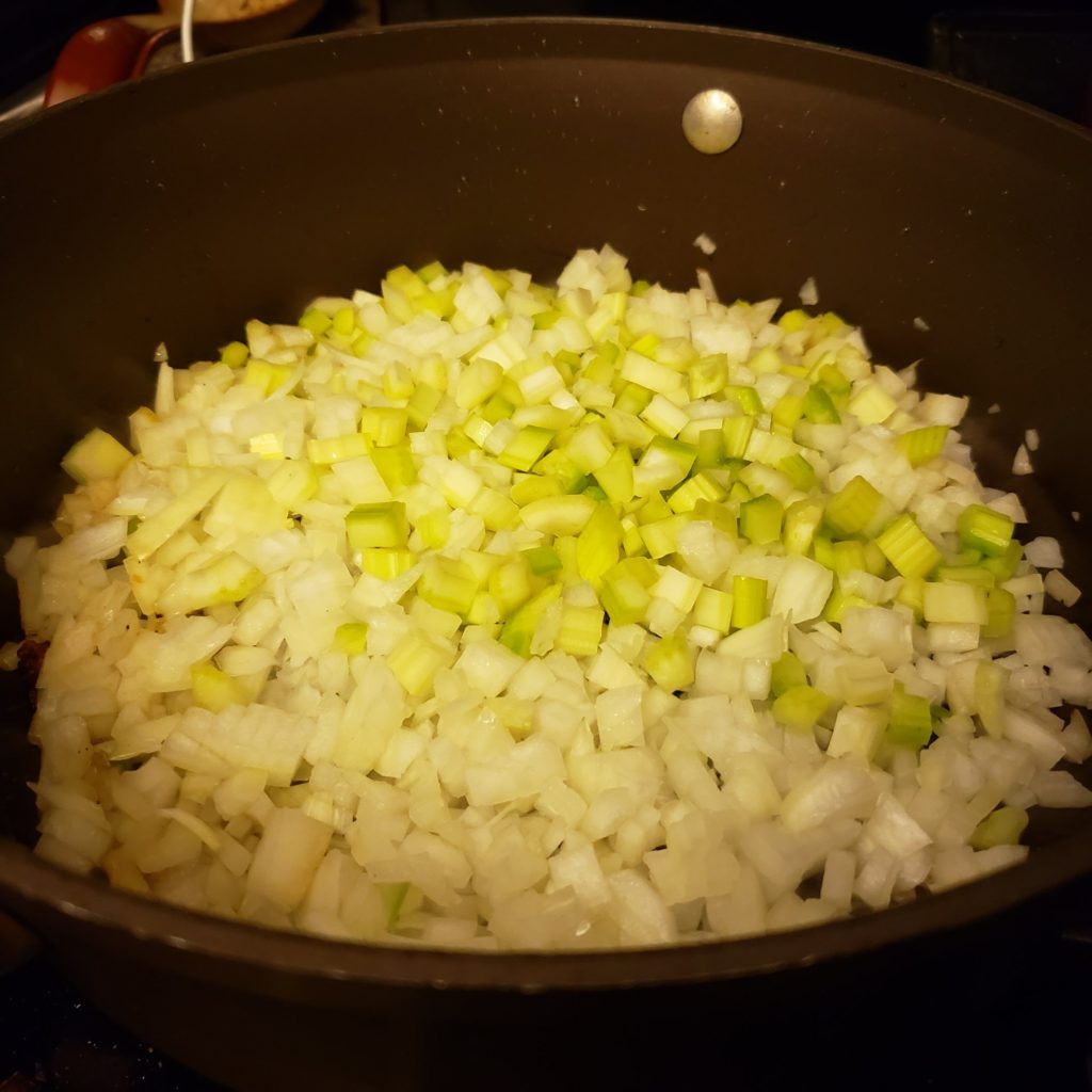 Onions and celery frying in a pan for shepherd's pie