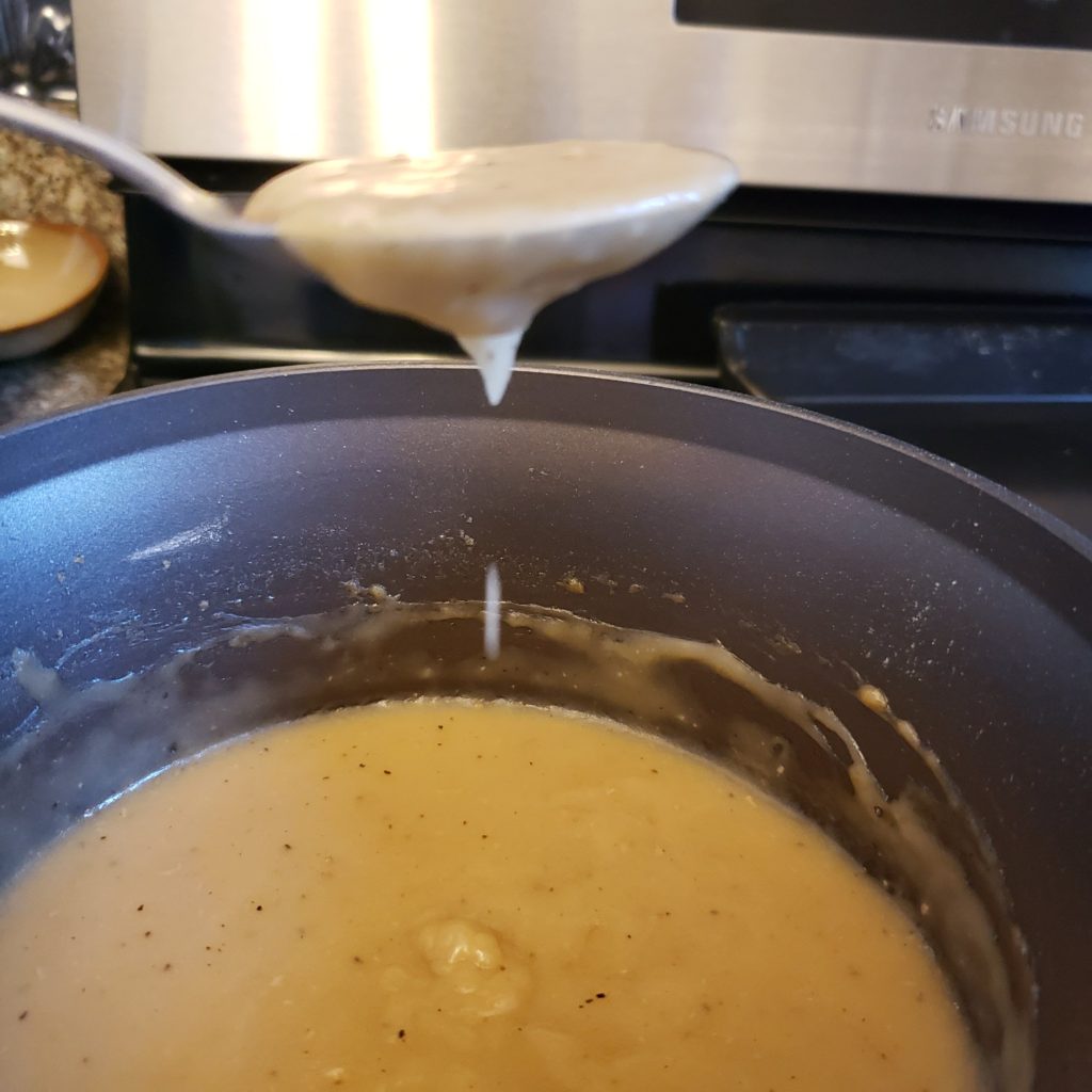 finished bechamel dripping from a spoon