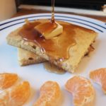 square pancake on a white plate with orange slices in front