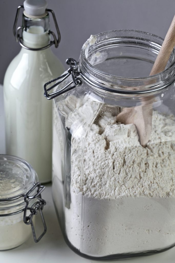 Self-rising flour in an clear glass jar, with milk and salt in the background 